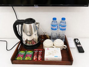 A tray with a coffee maker, two water bottles, a remote control, and a box of facial tissues. - Phousi Aphay Hotel (Luang Prabang)