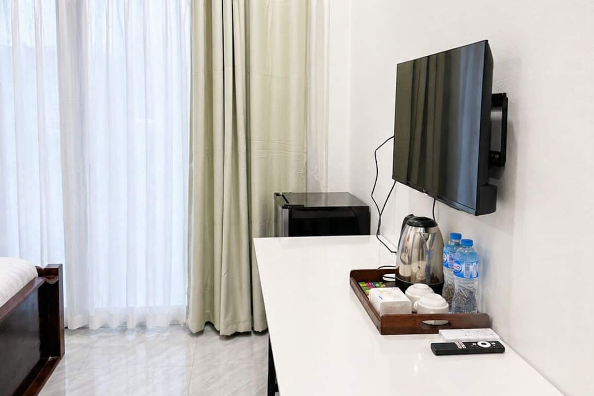 A hotel room with a bed, a desk with a flat-screen TV, a coffee maker, and a tray with toiletries.
