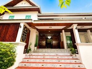 A traditional building with a staircase leading to the entrance, a wooden facade, and a signboard. - Phousi Aphay Hotel (Luang Prabang)