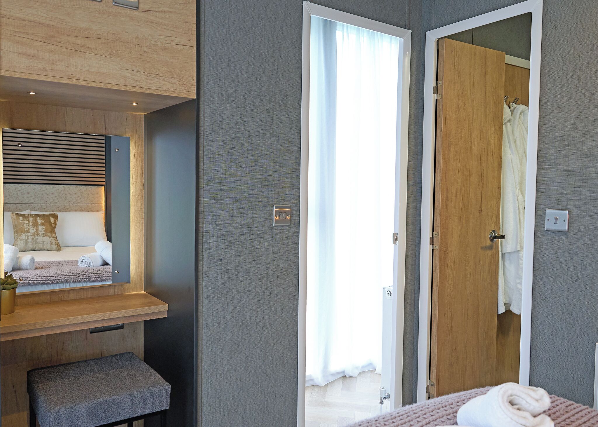 Une chambre moderne avec un banc intégré, une table de chevet et un grand miroir.