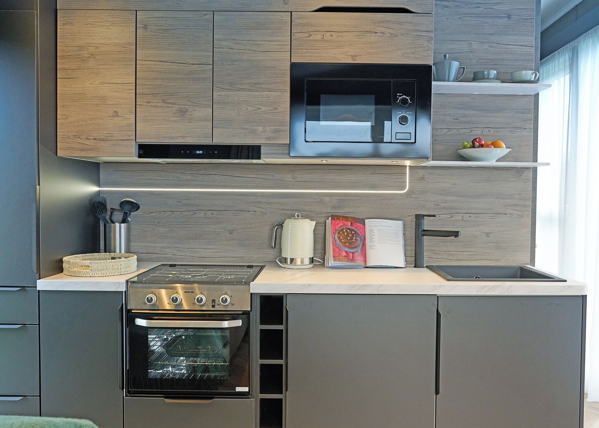 A modern kitchen with a built-in oven, microwave, and stainless steel appliances.