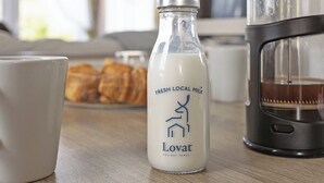 En flaska med färsk, lokal mjölk, en vit mugg och en kaffebryggare står på ett träbord.