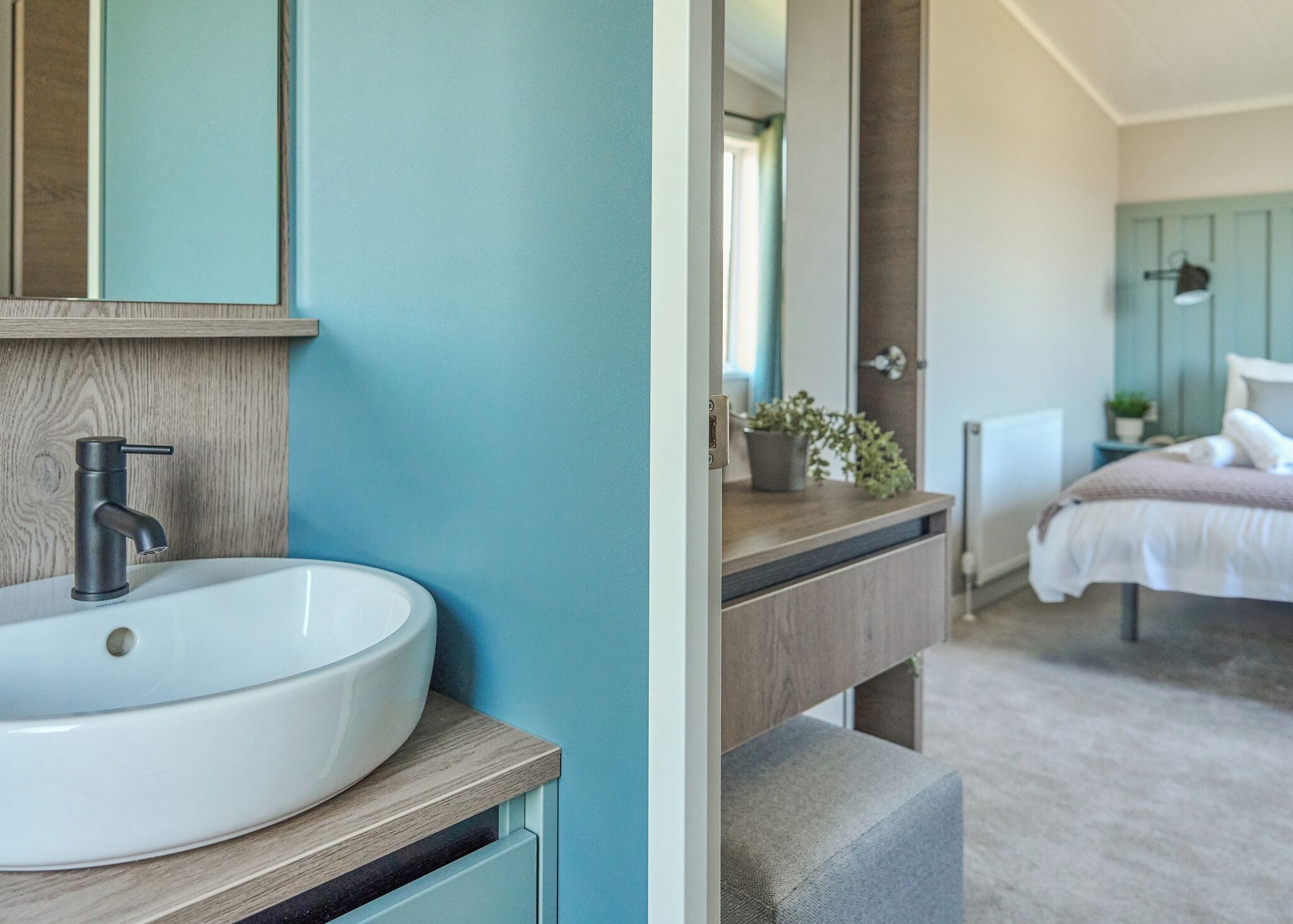 A bathroom with a white sink, a modern faucet, and a mirror above it.