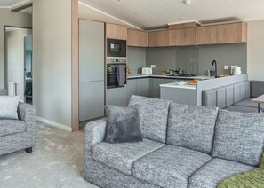 Eine moderne Küche mit integrierten Geräten, ein graues Sofa und eine kleine Essecke.