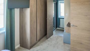 A room with a large wardrobe, a bed, and a door leading to another room.