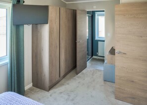 Une pièce comprenant une grande armoire, un lit et une porte donnant sur une autre pièce.