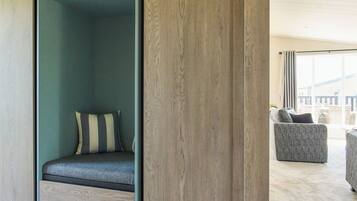 A modern room with a built-in bench, a grey upholstered chair, and a large window offering a view.