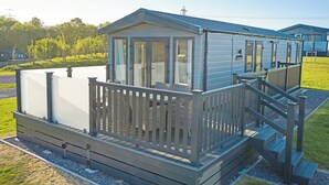 A mobile home with a deck, a small porch, and a staircase leading to the entrance. - Premium Hot Tub 4 bedroom Holiday Home sleeps 8 (Landford, Nr Salisbury)