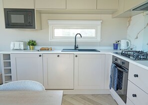 Eine kleine Küche mit Mikrowelle, Toaster, Spüle, Herd und Backofen.