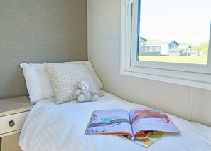 A bedroom with a bed, a window, a teddy bear, and an open book. - Premium Hot Tub 4 bedroom Holiday Home sleeps 8 (Landford, Nr Salisbury)