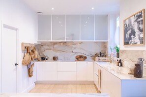 Eine moderne Küche mit weißen Schränken, einer Marmor-Spritzschutzwand und einer Pendelleuchte.