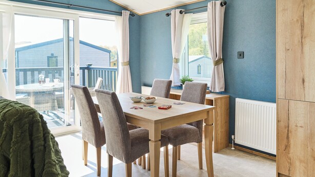A dining area with a table, chairs, and a view of the outside. - Exclusive 2 bedroom Sauna Lodge sleeps 4 (Landford, Nr Salisbury)