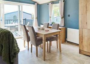 Un espace repas comprenant une table, des chaises et donnant sur l’extérieur.