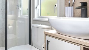 Ein Badezimmer mit weißem Waschbecken, Toilette und Duschkabine.