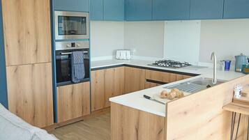 A modern kitchen with wooden cabinets, a built-in oven, a gas stove, and a sink.