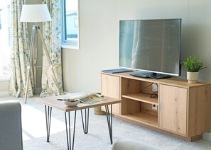 A modern living room with a flat-screen TV, wooden cabinet, and a small table with a bowl and magazine. - Exclusive 2 bedroom Lodge sleeps 4 (Pet) (Landford, Nr Salisbury)