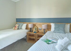 A hotel room with two single beds, a wooden headboard, bedside lamps, a small wooden nightstand, and a teddy bear. - Exclusive 2 bedroom Lodge sleeps 4 (Pet) (Landford, Nr Salisbury)