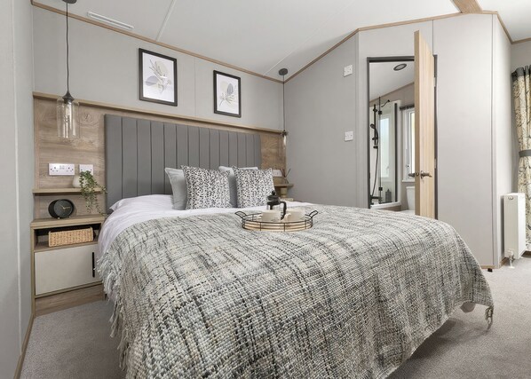 Ein Schlafzimmer mit einem Bett, Nachttischen, einem Wandregal, einem gerahmten Bild und einer Tür zu einem anderen Raum.