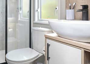 Ein Badezimmer mit weißem Waschbecken, Toilette und Duschkabine.