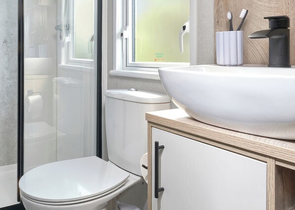 Un baño con lavamanos blanco, inodoro y cabina de ducha.