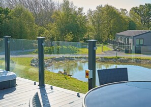 A pool with a glass barrier, a deck, and a building in the background.