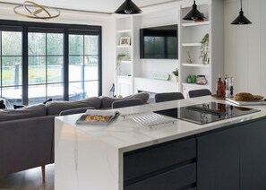 Una cocina moderna con una isla central, electrodomésticos integrados y un área de comedor con sofá.