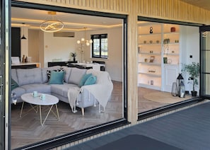 An open-plan living area with a sofa, coffee table, and a dining area with a table and chairs. - Autograph Kos Hot Tub 2-bedroom Luxury Lodge slp 4 (Landford, Nr Salisbury)