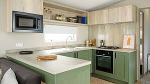Een moderne keuken met een ingebouwde magnetron, een gasfornuis en een spoelbak.