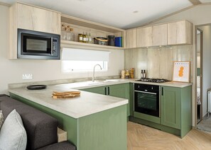 A modern kitchen with a built-in microwave, a gas stove, and a sink. - A stylish and contemporary retreat designed with comfort and quality in mind. (Peterborough)