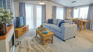 Ein Wohnzimmer mit einer Couch, einem Couchtisch, einem Fernseher und einem Essbereich mit Tisch und Stühlen.