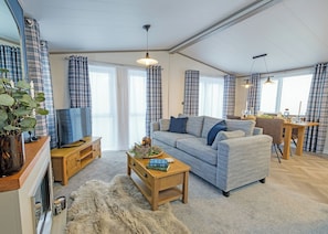 Ein Wohnzimmer mit einer Couch, einem Couchtisch, einem Fernseher und einem Essbereich mit Tisch und Stühlen.