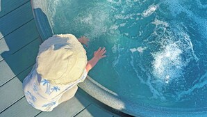 Eine Person mit Hut, die den Rand eines Pools berührt.