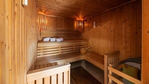 Eine Holzsauna mit Bänken, eine Bank mit Handtüchern und einem Holzeimer.