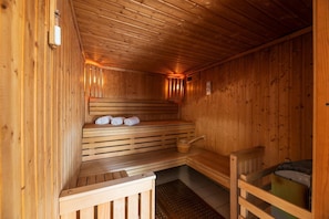A wooden sauna with benches, a bench with towels, and a wooden bucket. - Seaside apartment in Saint-Palais-sur-Mer (Saint-Palais-sur-Mer)