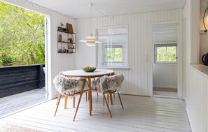 Ein Zimmer mit einem runden Tisch, zwei Stühlen, einer Obstschale, einem Regal mit Dekoration und einem Fenster.