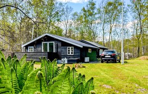 A cabin with a sloped roof, a car parked in front, and a lush green lawn. - 2 bedroom stunning home in Hadsund (Hadsund)