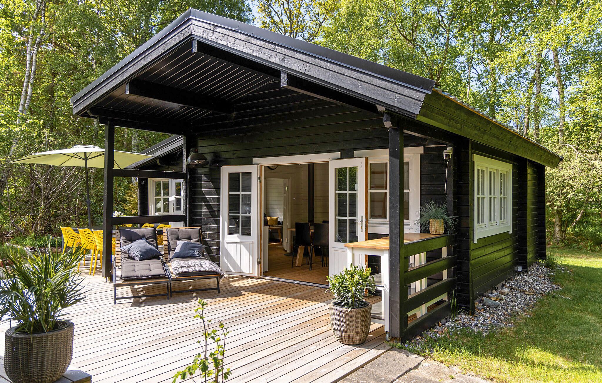 A wooden cabin with a deck, outdoor seating, and a covered patio area.