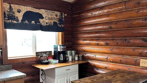 A cabin kitchen with wooden walls, a coffee station, and a bar area.