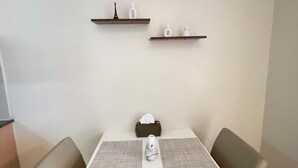Une table à manger avec deux chaises, un vase et deux étagères ornées d’objets décoratifs.
