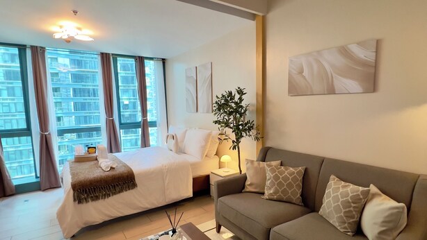 Une chambre d’hôtel moderne équipée d’un lit, d’un canapé, d’une table basse et d’une grande fenêtre avec des rideaux.