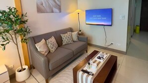 Un salon avec un canapé, une table basse, un téléviseur et une plante.