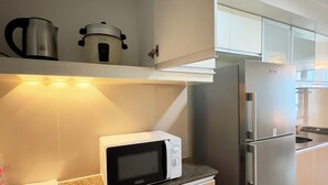 Une cuisine moderne équipée d’un four à micro-ondes, d’une bouilloire et d’un réfrigérateur en acier inoxydable.