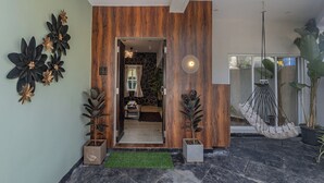 A modern interior with a wooden accent wall, a hanging chair, and potted plants. - ELIVAAS Moonlit retreat 3 BHK with Pool (Alibag)