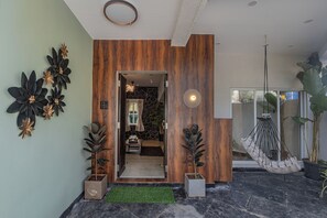 A modern interior with a wooden accent wall, a hanging chair, and potted plants. - ELIVAAS Moonlit retreat 3 BHK with Pool (Alibag)