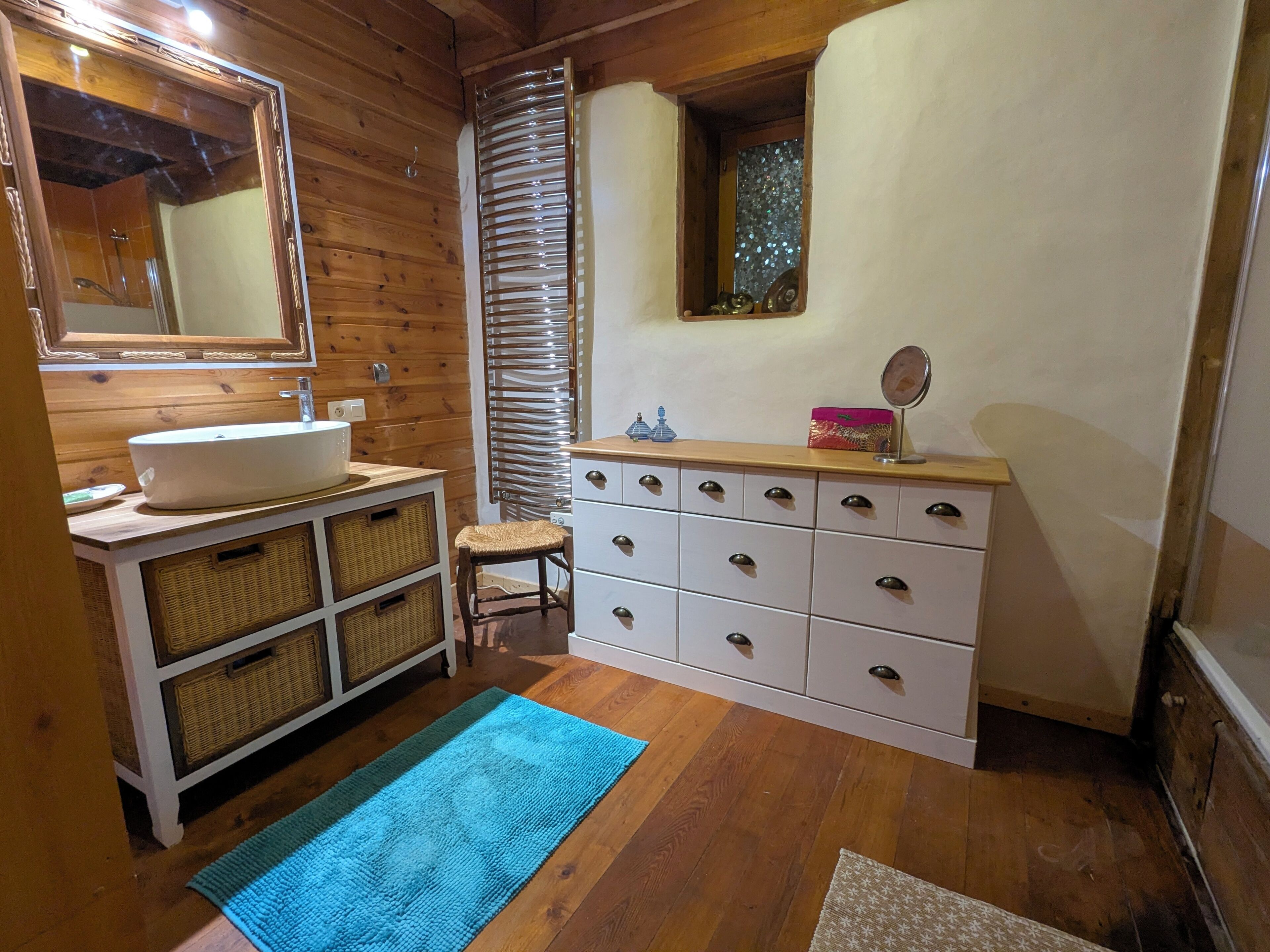 A bathroom with a wooden vanity, a sink, a mirror, and a window.