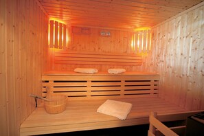 Eine Sauna mit Holzwänden, einer Sitzbank, einem Eimer und Handtüchern.
