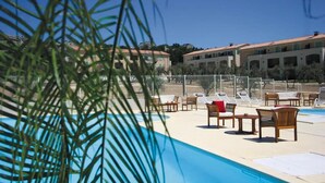 Un área de piscina con sillones de descanso y vistas a edificios de hotel.