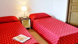 Ein Zimmer mit zwei Einzelbetten, einem Nachttisch mit Lampe und einer Zeitschrift auf dem Boden.
