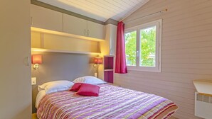 A bedroom with a bed, bedside lamps, a window with curtains, and a built-in shelf. - Cottage by the river in Nouvelle-Aquitaine (Castelmoron-sur-Lot)