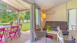 A modern interior with a wooden deck, a sofa, a table, and chairs. - Cottage by the river in Nouvelle-Aquitaine (Castelmoron-sur-Lot)